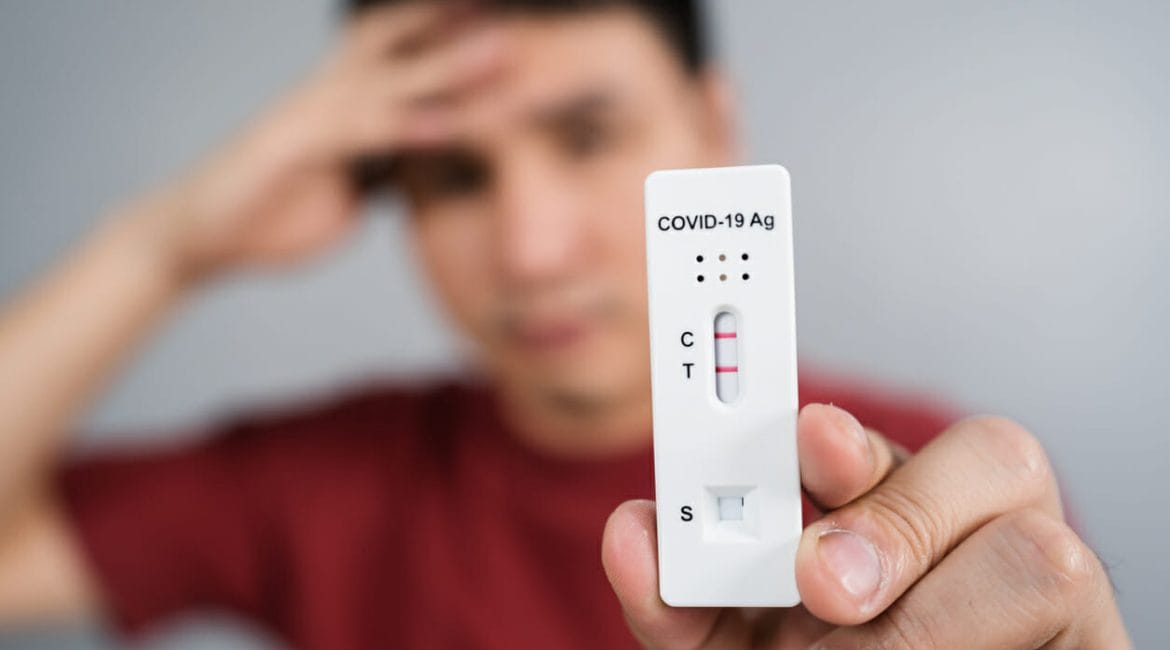 man holding Covid-19 positive test